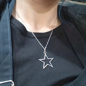 Detailed close-up of hollow star pendant necklace worn over dark textured garment