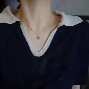 Elegant gold chain necklace with Hetian jade pendant worn by a model in close-up