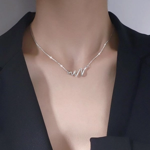 Minimalist silver wavy pendant necklace with zircons shown on a model in a black suit