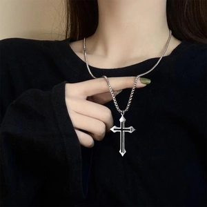 Close-up of a punk style titanium steel cross pendant necklace on a black shirt background