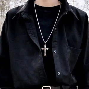Close-up of a silver punk cross pendant necklace on a black shirt for a gothic style