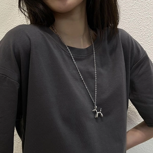 Close-up of a silver balloon dog pendant on a titanium steel chain worn by a model