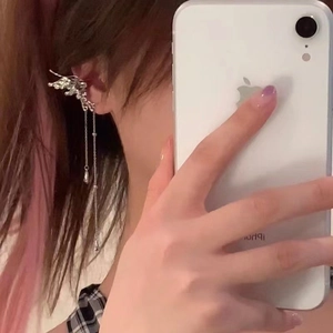 Détail d'un earcuff papillon argenté avec de longues chaînes à pompons et gouttes