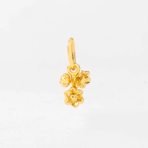 Macro view of three clustered gold floral pendants with detailed petal texture and ring