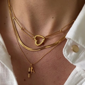Close-up of triple-layered 18K gold necklace with heart lock and letter A pendant
