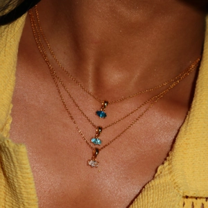 Detail of triple layered gold necklaces with marquise-cut gems in blue and clear tones
