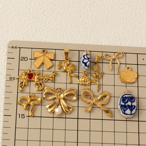 Selection of 18K gold plated bow and angel charms with ceramic beads on a beige mat