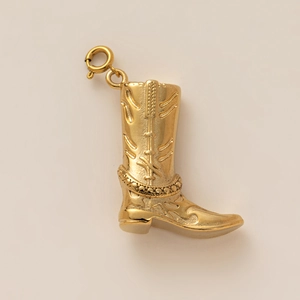 Detailed close-up of a golden western cowboy boot pendant with embossed patterns