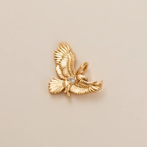 Vue détaillée d'un pendentif aigle doré avec cristal incrusté et plumes finement ciselées