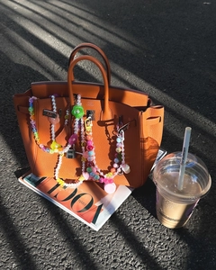 Close-up of colorful beaded bag charm with ice cream and flower beads on orange handbag