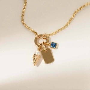 Détail du collier doré avec pierre carrée bleue médaille en métal et breloque glace perle