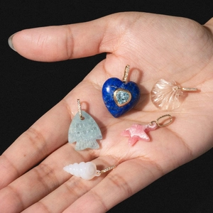 Hand holding colorful heart, fish and seashell jewelry pendants with gold diamond clips