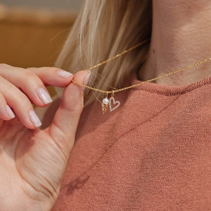 Collier doré vintage français avec pendentifs cœur et perle sur un modèle élégant