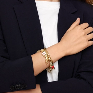 Detail of 18K gold-plated bracelet with strawberry and poker charms on blue blazer