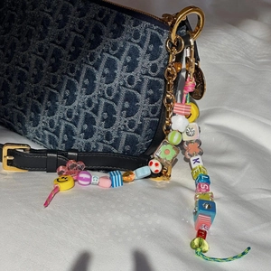 Rainbow beaded keychain with letters and smile face charm on a luxury canvas bag
