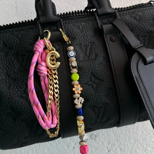 Bubble letter C keychain with colorful beads and woven strap on a black bag