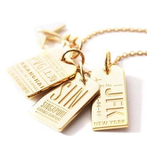 Detail of 18K gold luggage tag pendants with international airport codes and plane charms