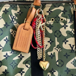 Detail of luxury bubble letter K keychain and heart charm on camouflage monogram bag