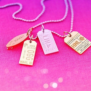 Macro detail of Hawaii airport tag pendants in gold and silver finish with ball chain