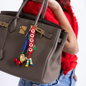 Detail of colorful cherry and heart charm pendant on a woven cord for luxury handbags