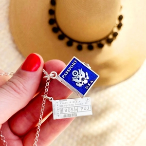 Detailed view of silver necklace with blue USA passport and boarding pass pendants