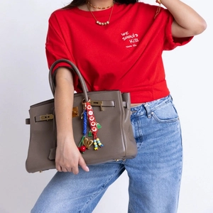 Detail of colorful bead charm on gray pebbled leather handbag with metallic closure