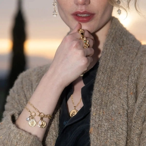 Nahaufnahme eines goldenen Schmucksets mit Münzanhängern und Perlen am Model