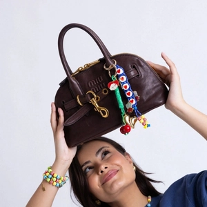 Detail of dark brown leather handbag with colorful heart and cherry bag charms