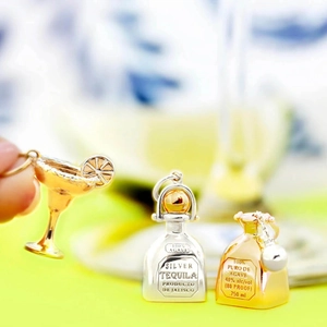 Detailed macro view of gold cocktail glass and silver tequila bottle charms