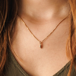 Dettaglio della collana con ciondolo a croissant in oro lucido indossata da modella