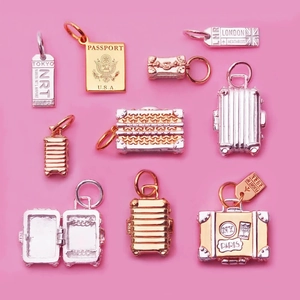 Detailed macro view of travel charms featuring tiny metal suitcases and passport charms