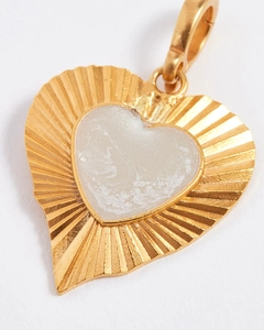Macro shot of gold heart pendant with radial textures and white shell inlay detail