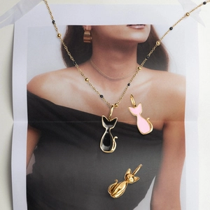 Detalle de lindos colgantes de gato en esmalte dorado, negro y rosa con collar de perlas