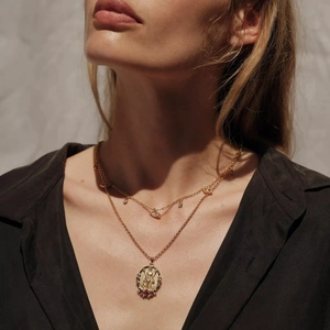 Nahaufnahme der doppelten Goldkette mit religiösem Relief-Anhänger und lila Edelstein
