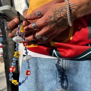 Detailed close-up of a beaded phone strap with cloud, mushroom and star charms
