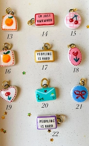 Nahaufnahme von handbemalten Anhängern mit Blumen- und Fruchtmotiven und Goldringen
