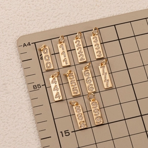 Golden 18K plated number pendants 000-999 with zircon inlay on a grey scale mat