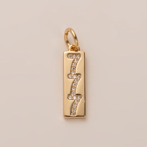 Detailed close-up of a 18K gold rectangular pendant featuring 777 crystal numerals