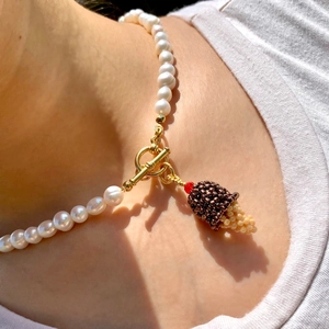 Gros plan d'un collier de perles blanches avec fermoir à bascule doré et pendentif