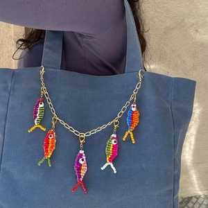Detail of colorful handmade beaded fish charms on a gold chain for bag decoration