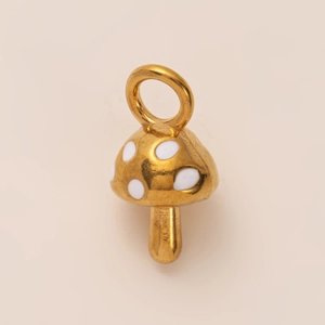 Close-up of golden mushroom pendant with white enamel dots and 18K gold plating
