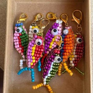 Detailed view of six colorful handmade beaded fish keychains in a gift box packaging