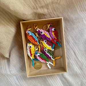Close-up of colorful beaded fish keychains in a gift box with golden lobster clasps