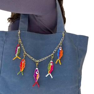 Colorful handmade beaded fish keychain with gold metal chain on a blue tote bag
