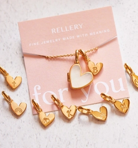 Detail van een 18K vergulde hartmedaillon met parelmoer en hangers met letters