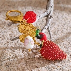 Golden keychain featuring a red strawberry pendant, porcelain bead, and golden leaf charms