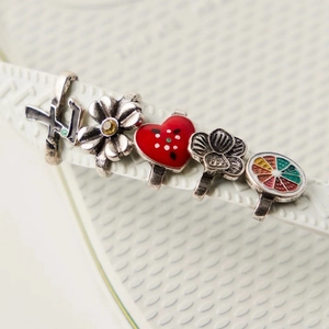 Macro-opname van kleurrijke emaille en strass bedeltjes op witte slippers-bandjes