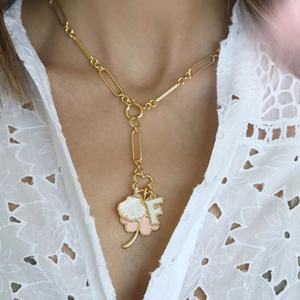 Close-up of golden paperclip chain necklace with shell and letter F pendant on model