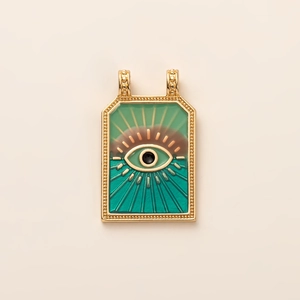 Detailed close-up of a gold tarot pendant featuring a green evil eye and enamel inlay