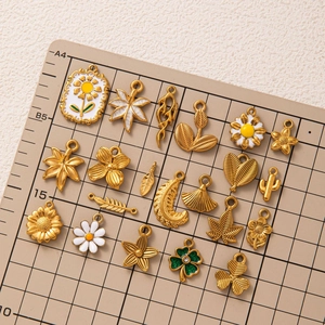18K gold plated stainless steel ocean shell and botanical pendants on a measuring grid
